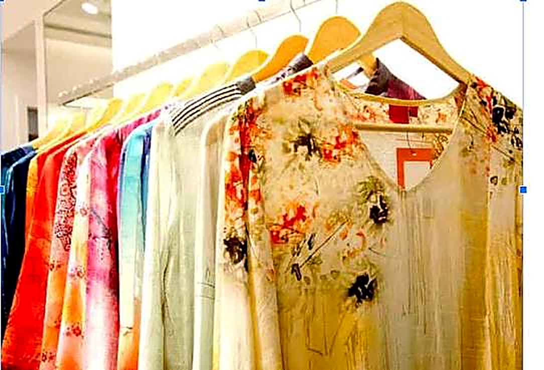 Vibrant collection of printed women's fashion apparel, kurtas, and dresses on wooden hangers